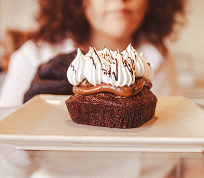 Plato con un pastelito de dulce de leche, chocolate y nata