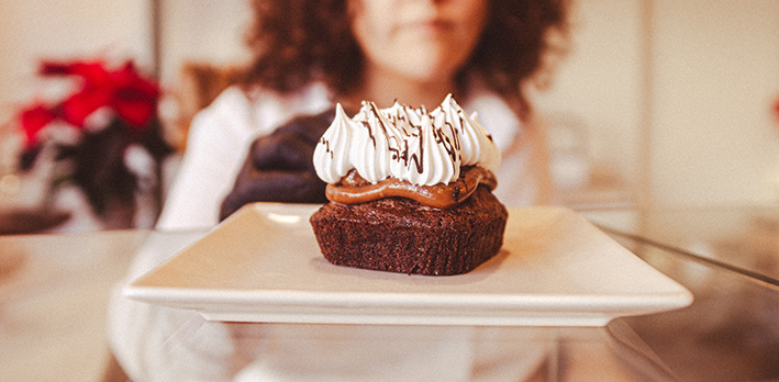 Plato con un pastelito de dulce de leche, chocolate y nata